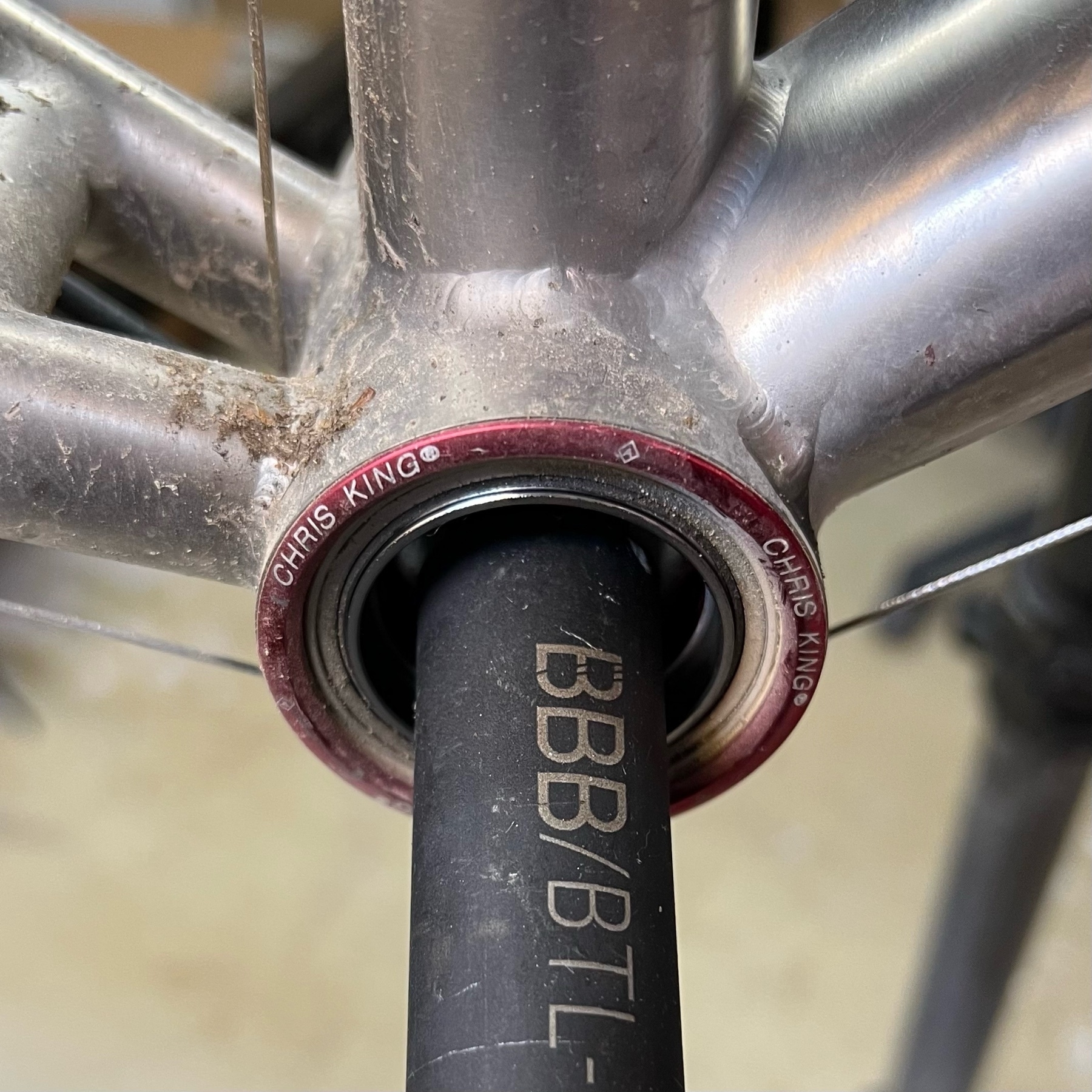 Red-anodised Chris King Pressfit 30 bottom bracket in a titanium bicycle frame. An extraction tool hanging in the bottom bracket. The frame around the bottom bracket is slightly sandy.