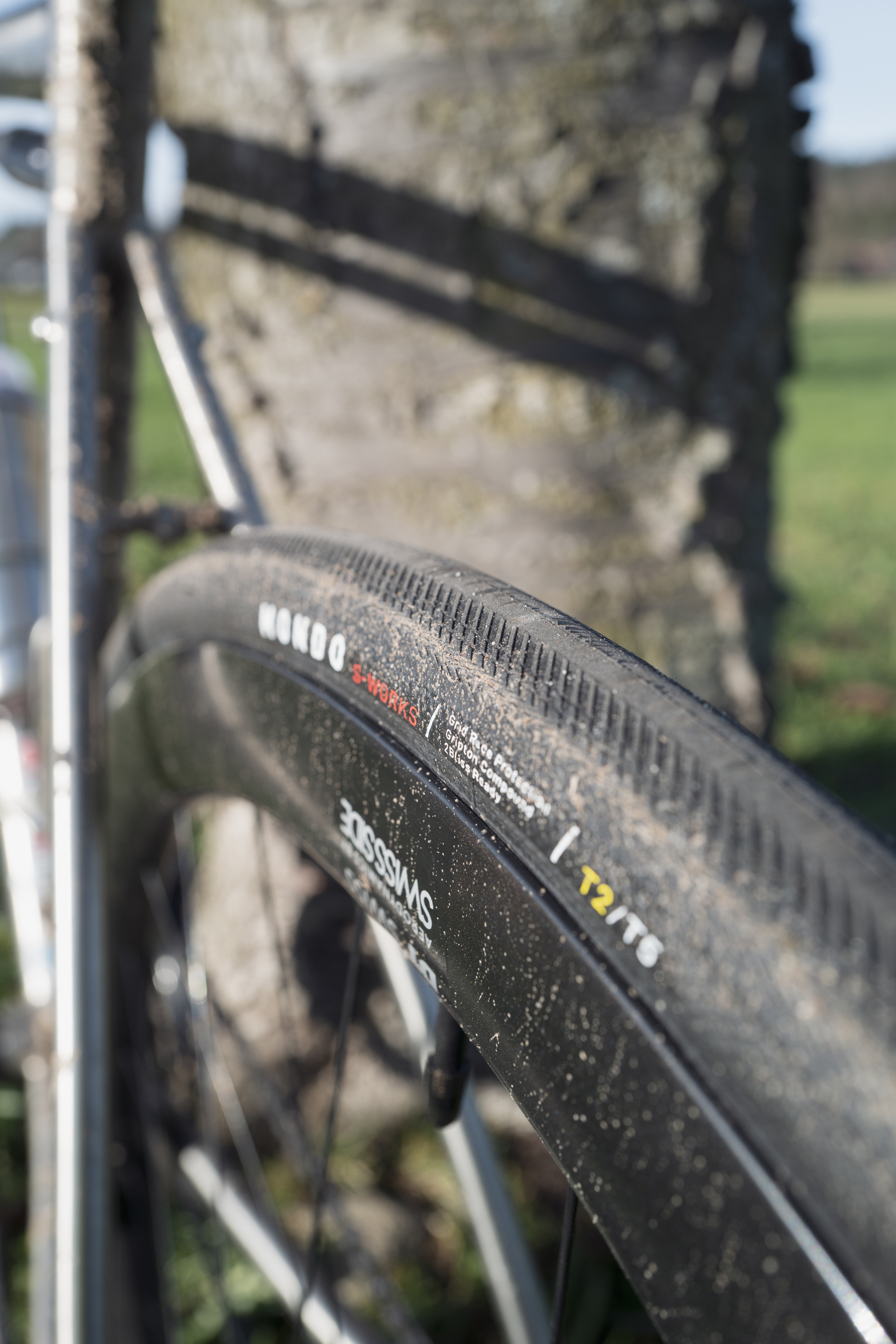 Close-up photo of a black road bike tire in a 2/3 orientation showing the logo on the sidewall and the tire tread in startk focus.