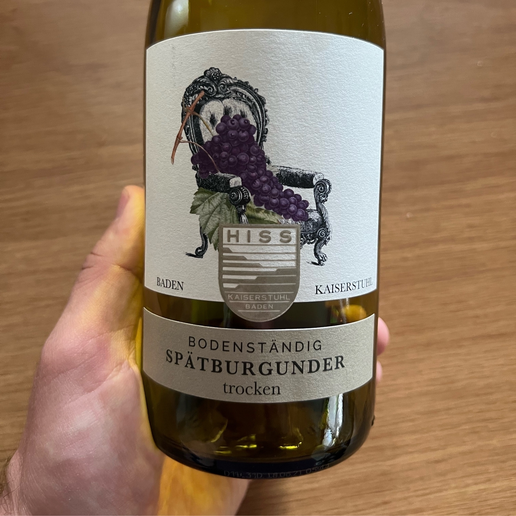 Untere Hälfte einer grünen Weinflasche mit Fokus auf das Etikett. Weinsorte: Spätburgunder, trocken; Jahrgang: 2019